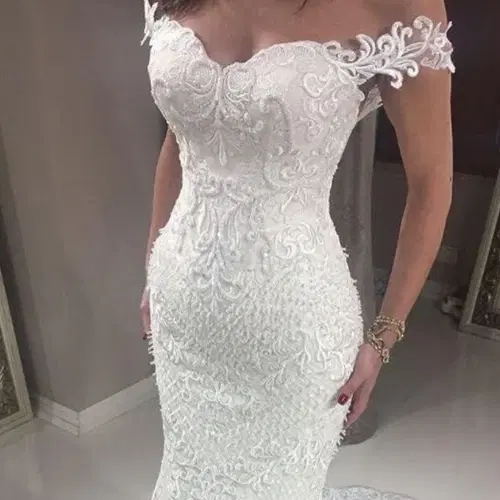 Robe de mariée sirène blanche en dentelle brodée, à épaules dénudées et mancherons de dentelle